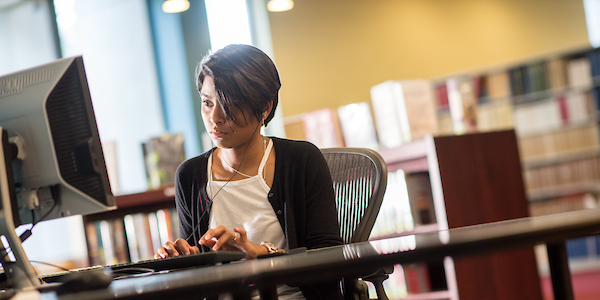 A young lady registers for her classes on a library computer